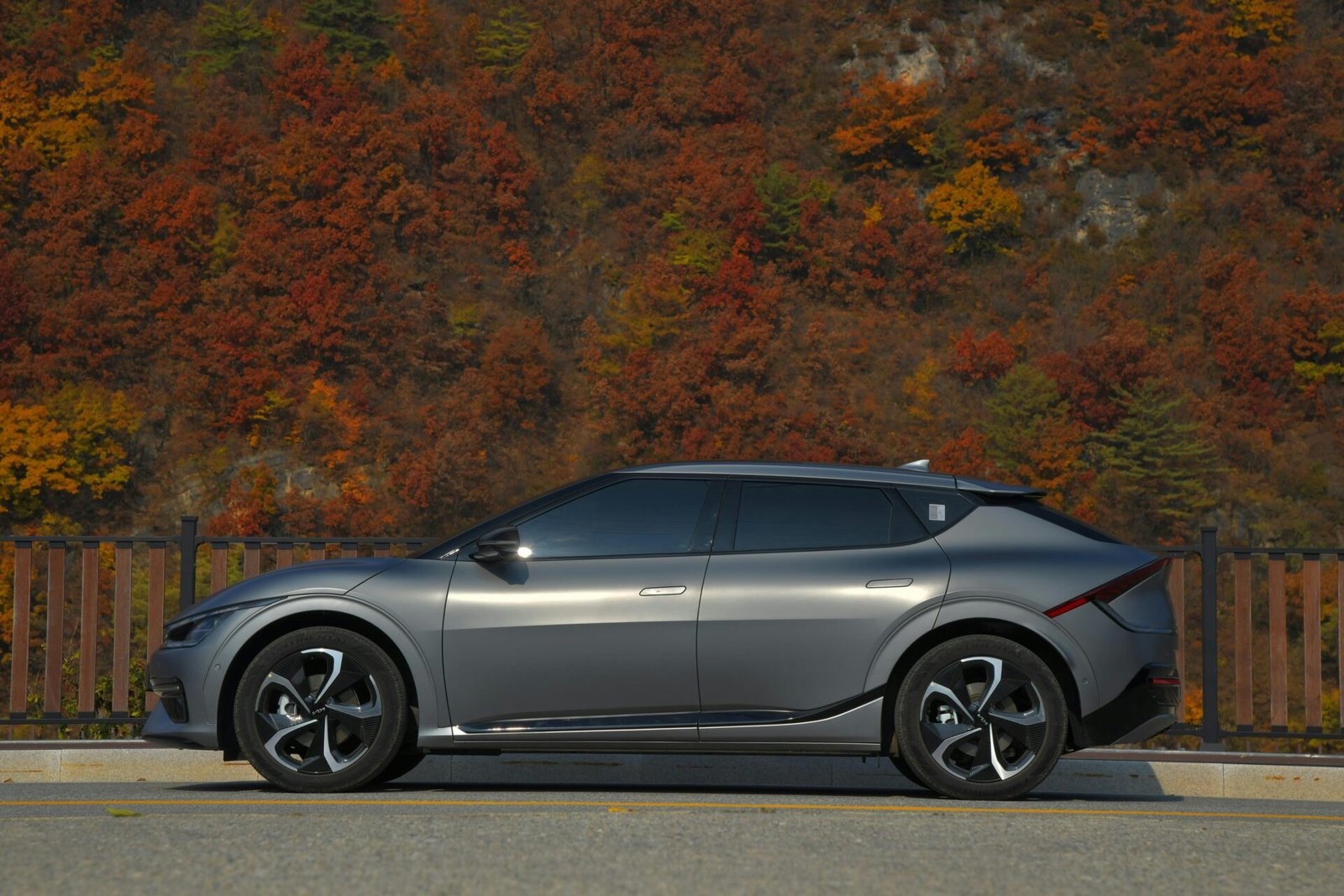 a silver car parked on the side of a road with trees in the background