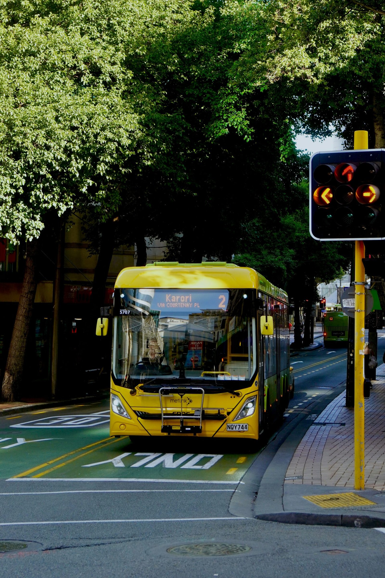 a yellow bus driving down a street next to a traffic light